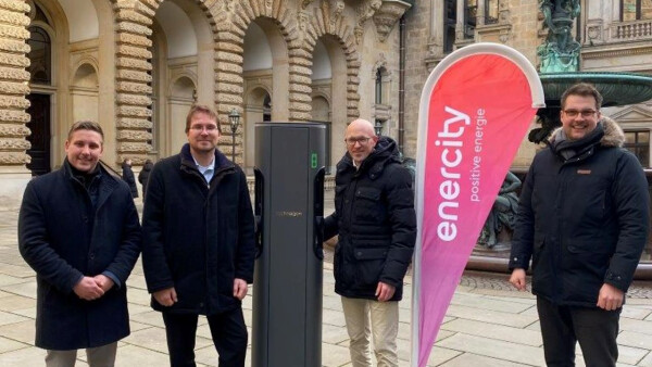 Vier Personen stehen an einer Stromladesäule