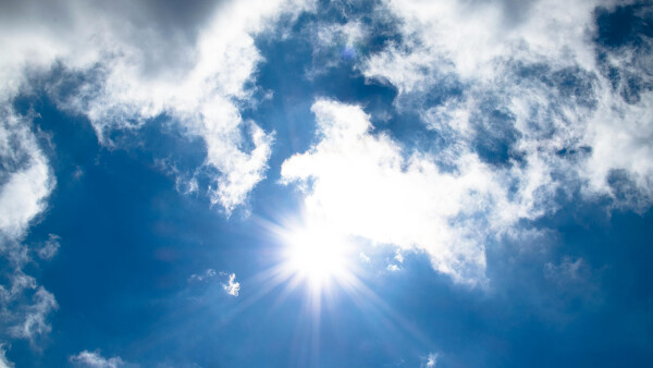Himmel mit kleinen Wolken und Sonnenstrahlen.