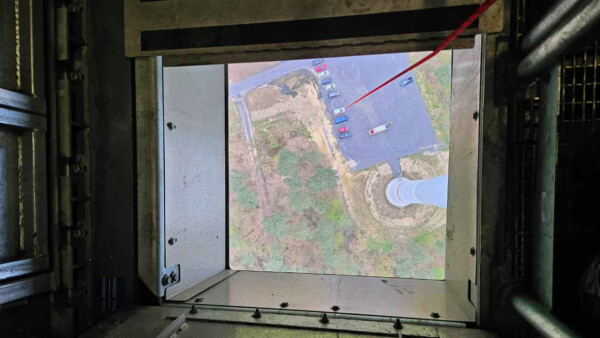 Blick aus einer Bodenluke von einer Windenergieanlage nach unten auf den Boden