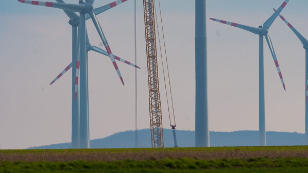 Windenergieanlagen auf einem Feld mit Baukran im Vordergrund